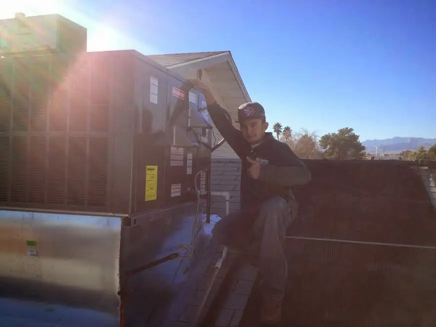 HVAC technician performing Heat Pump Repair on a rooftop unit in Dunlap